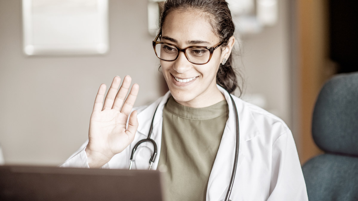 A physician is waving behind a computer equipped with the program eSante.